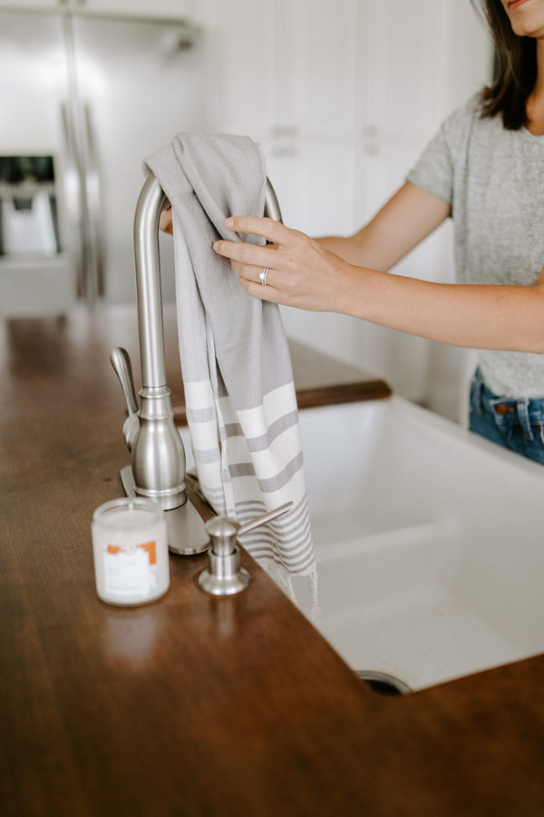turkish cotton hand towel with fringes hanging from a faucet