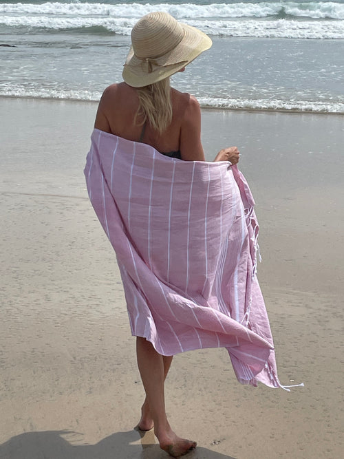 blond woman on beach with a pink turkish towel